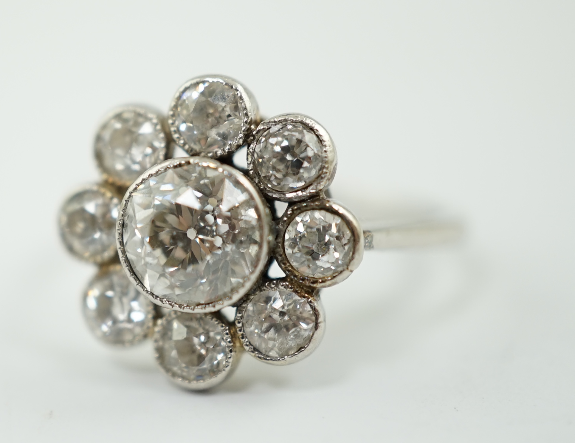 A platinum? and millegrain set nine stone diamond flower head cluster ring